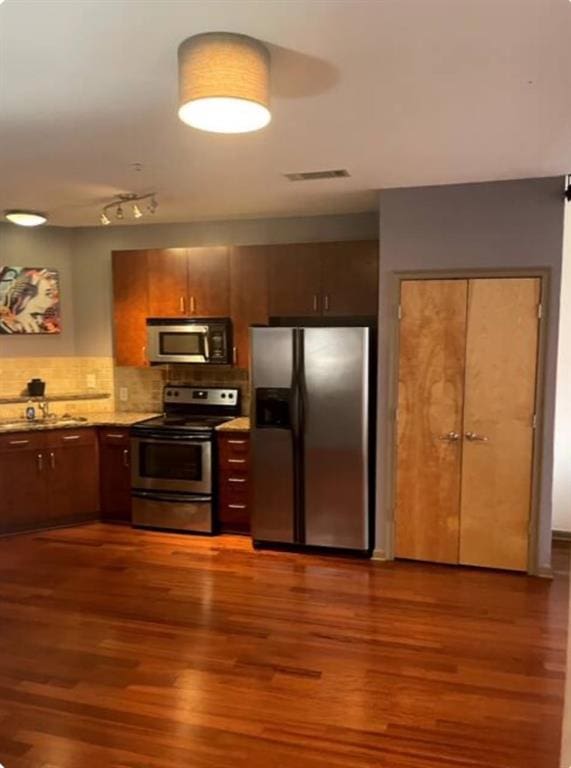 kitchen featuring dark hardwood / wood-style flooring, backsplash, stainless steel appliances, and sink