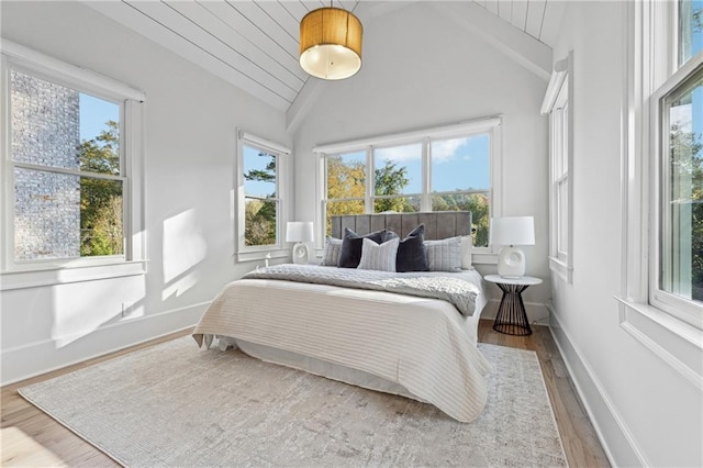 bedroom featuring multiple windows, hardwood / wood-style flooring, wood ceiling, and vaulted ceiling with beams