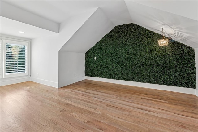 additional living space with light hardwood / wood-style floors and vaulted ceiling