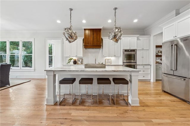 kitchen featuring a breakfast bar, stainless steel appliances, decorative light fixtures, white cabinets, and a kitchen island