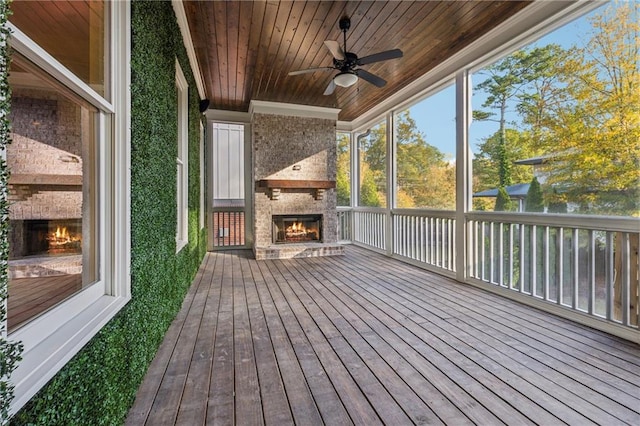 wooden terrace featuring an outdoor stone fireplace and ceiling fan