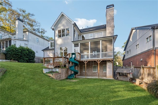 back of house featuring a sunroom, a patio, and a lawn