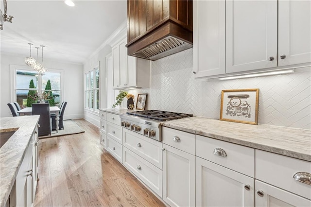 kitchen with custom exhaust hood, pendant lighting, light hardwood / wood-style flooring, white cabinets, and stainless steel gas stovetop