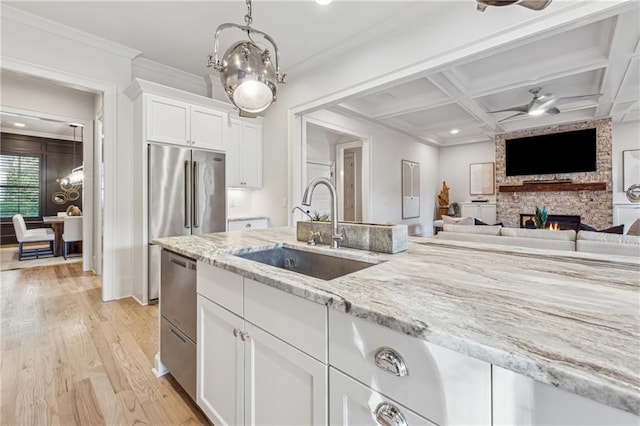 kitchen featuring coffered ceiling, white cabinets, sink, a fireplace, and light hardwood / wood-style floors