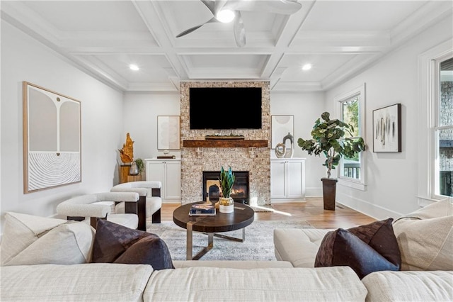 living room featuring light wood-type flooring, coffered ceiling, ceiling fan, beam ceiling, and a fireplace