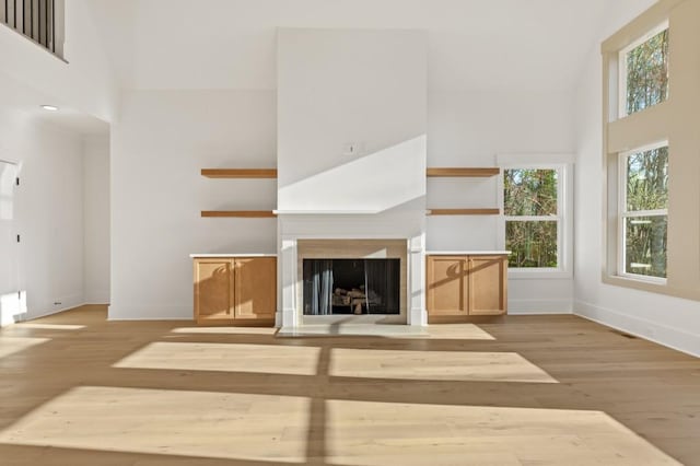 2410 Glade Overlook, Cumming, GA 30041 - unfurnished living room featuring wood finished floors, a towering ceiling, and a fireplace with flush hearth