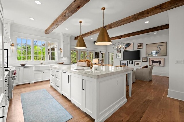 1141 Ragley Hall Rd NE, Brookhaven, GA 30319 - kitchen featuring a sink, beamed ceiling, a spacious island, white cabinets, and decorative light fixtures