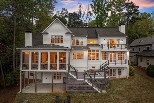 1141 Ragley Hall Rd NE, Brookhaven, GA 30319 - back of property at dusk featuring stairway, a balcony, a chimney, a patio, and a sunroom