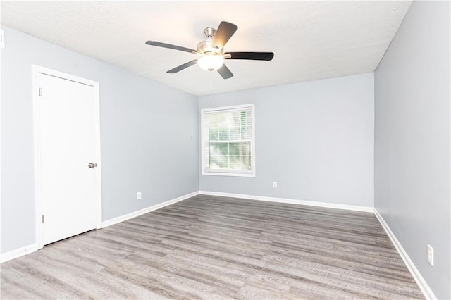 spare room with baseboards, a ceiling fan, wood finished floors, and a textured ceiling