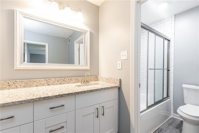 bathroom featuring vanity, visible vents, toilet, wood finished floors, and combined bath / shower with glass door