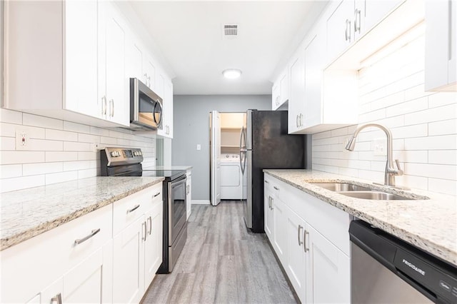 kitchen with white cabinetry, visible vents, a sink, washer / dryer, and stainless steel appliances