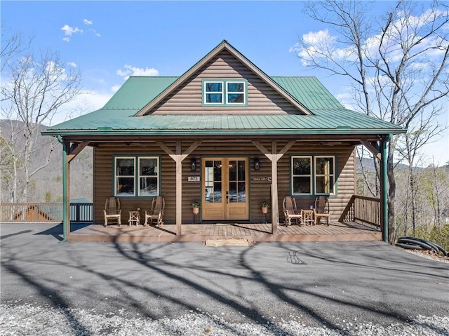 chalet / cabin with metal roof, a porch, log veneer siding, and french doors