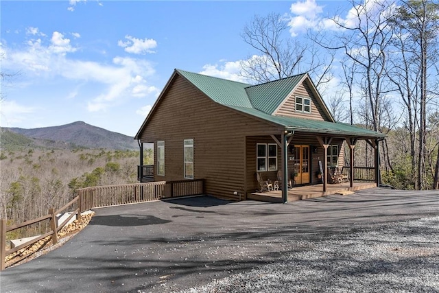 view of home's exterior with covered porch, log veneer siding, a mountain view, and metal roof