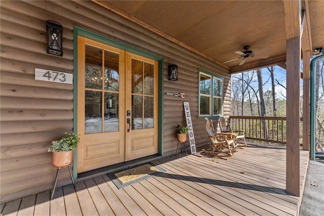 wooden deck featuring covered porch, ceiling fan, and french doors