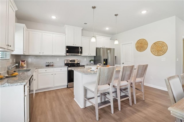 11113 Suria Dr, Covington, GA 30014 - kitchen with appliances with stainless steel finishes, light wood finished floors, tasteful backsplash, a breakfast bar, and recessed lighting