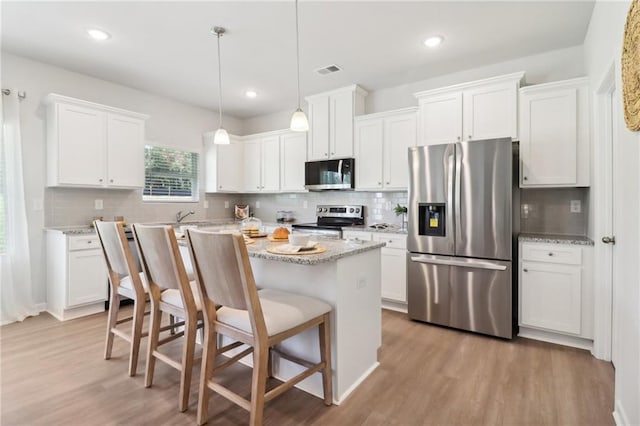 11113 Suria Dr, Covington, GA 30014 - kitchen featuring appliances with stainless steel finishes, light wood-type flooring, decorative backsplash, white cabinetry, and recessed lighting