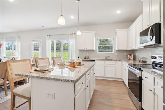 11113 Suria Dr, Covington, GA 30014 - kitchen with stainless steel appliances, a breakfast bar, a center island, tasteful backsplash, and white cabinetry