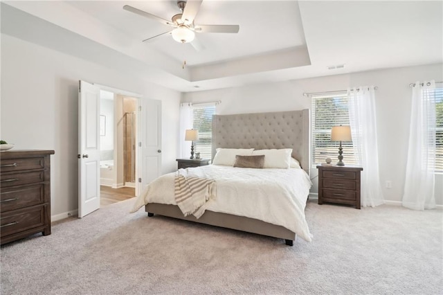 11113 Suria Dr, Covington, GA 30014 - bedroom with a tray ceiling, light carpet, ensuite bathroom, and a ceiling fan