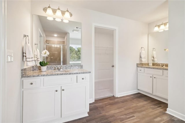 11113 Suria Dr, Covington, GA 30014 - full bathroom featuring a shower stall, wood finished floors, two vanities, and a walk in closet
