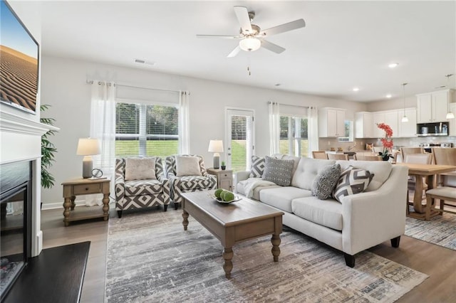 11113 Suria Dr, Covington, GA 30014 - living area with wood finished floors, a glass covered fireplace, a ceiling fan, and recessed lighting