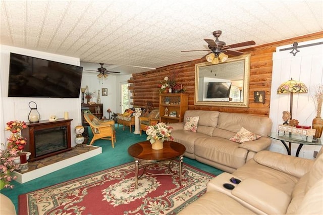 living area featuring carpet floors, log walls, ceiling fan, and a glass covered fireplace
