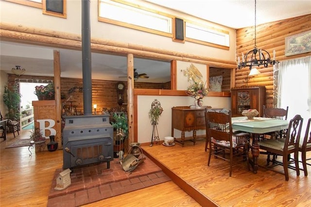 dining room featuring a wood stove, rustic walls, wood finished floors, and a healthy amount of sunlight