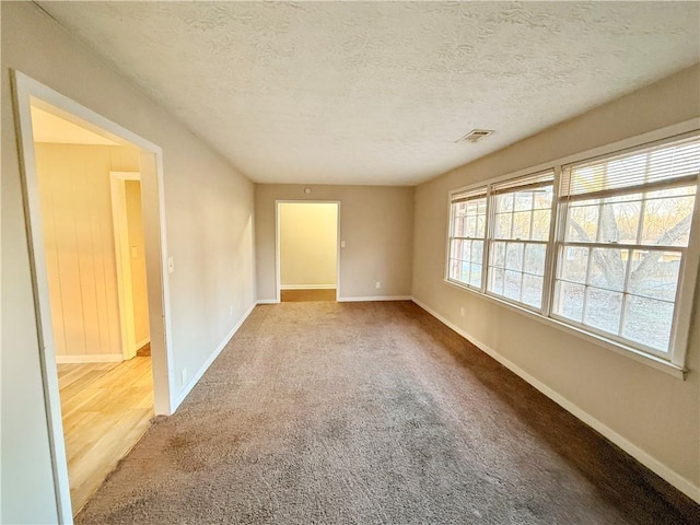 empty room with a textured ceiling and carpet floors