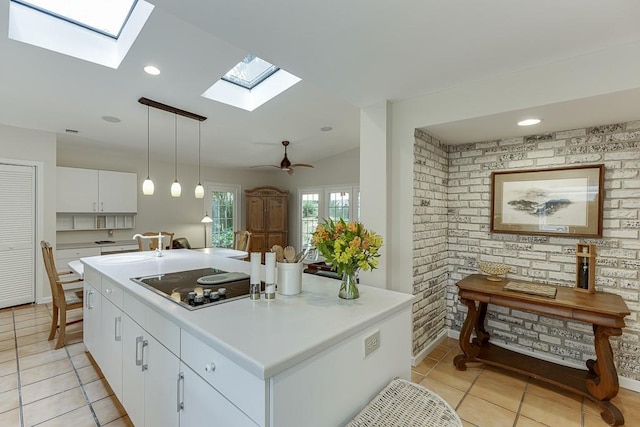 3219 Parkridge Cres, Chamblee, GA 30341 - kitchen with black electric cooktop, a skylight, light tile patterned floors, white cabinets, and a center island with sink