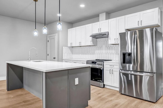 kitchen featuring sink, decorative light fixtures, appliances with stainless steel finishes, a kitchen island with sink, and white cabinets