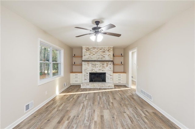 unfurnished living room featuring a fireplace, ceiling fan, and light wood-type flooring