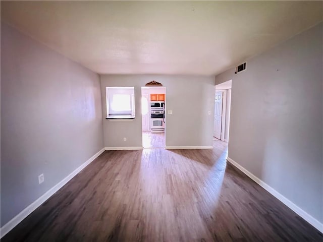 unfurnished living room featuring visible vents, dark wood-style flooring, and baseboards