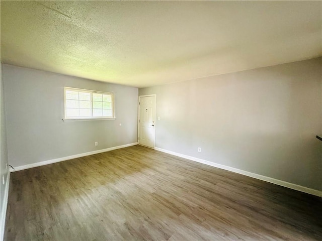 empty room featuring baseboards, a textured ceiling, and wood finished floors