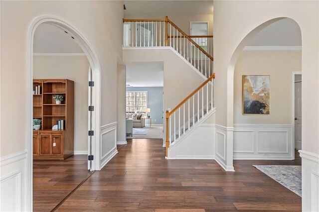 entryway featuring stairs, crown molding, a decorative wall, and wood finished floors