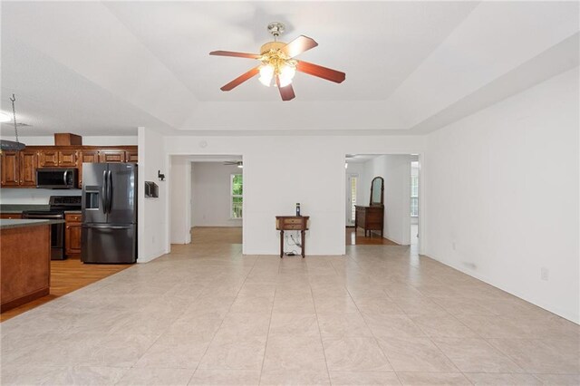 kitchen with light tile patterned floors, a raised ceiling, ceiling fan, and appliances with stainless steel finishes