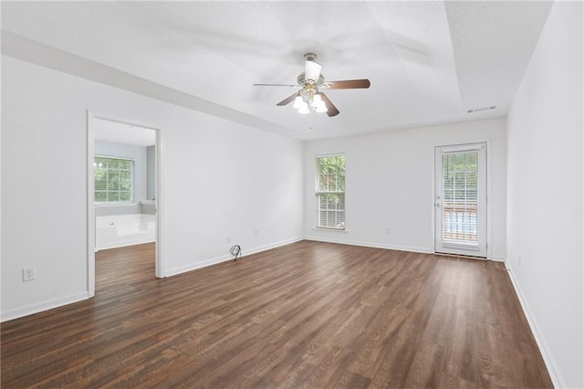 empty room featuring dark wood-type flooring, a wealth of natural light, and ceiling fan