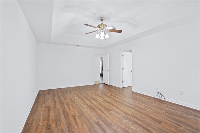 spare room with ceiling fan, dark hardwood / wood-style flooring, and a tray ceiling