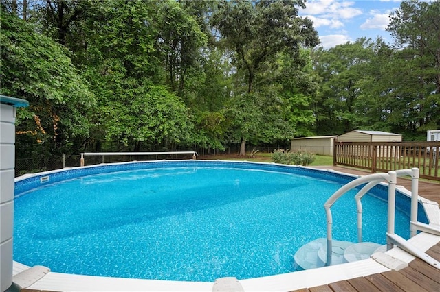 view of swimming pool with a wooden deck and a storage shed