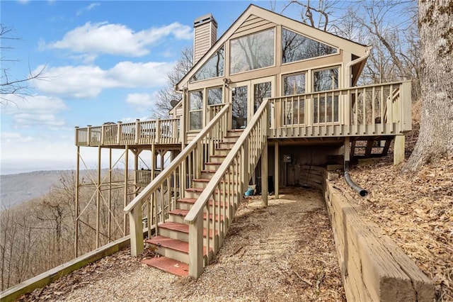 rear view of house with a deck, a chimney, and stairs