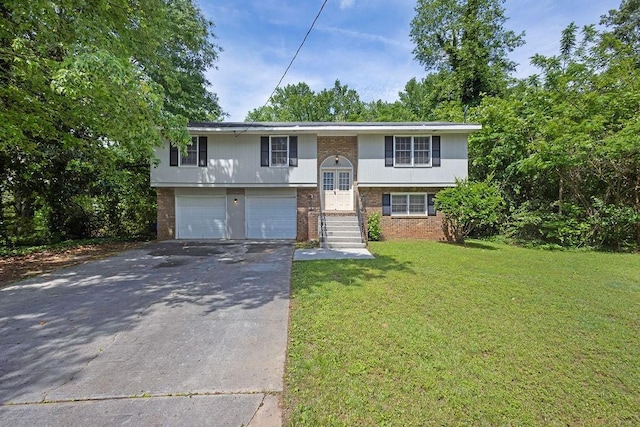 raised ranch with a garage, driveway, a front lawn, and brick siding