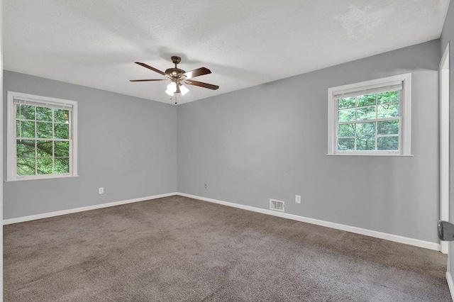 empty room featuring visible vents, a ceiling fan, baseboards, and carpet flooring