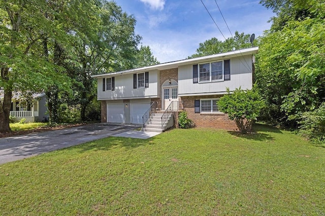 raised ranch featuring brick siding, a garage, a front yard, and aphalt driveway