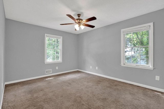 carpeted spare room with baseboards, a ceiling fan, and visible vents