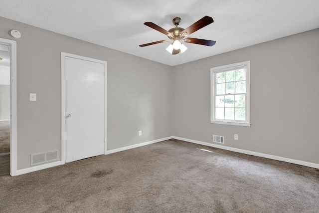 carpeted empty room featuring visible vents, baseboards, and ceiling fan