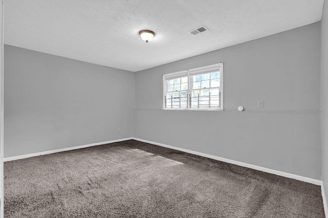 spare room featuring carpet flooring, a textured ceiling, baseboards, and visible vents
