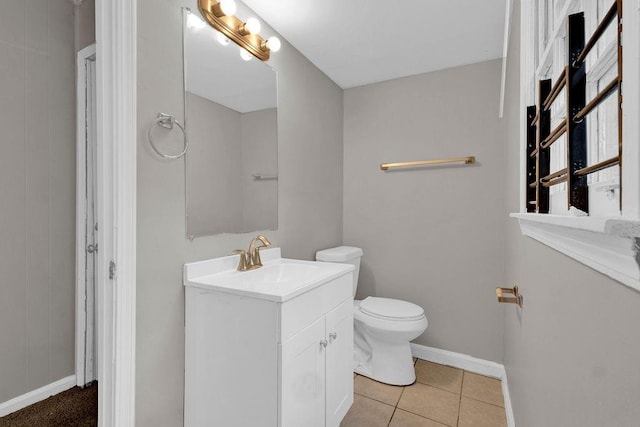 bathroom featuring vanity, baseboards, tile patterned flooring, and toilet