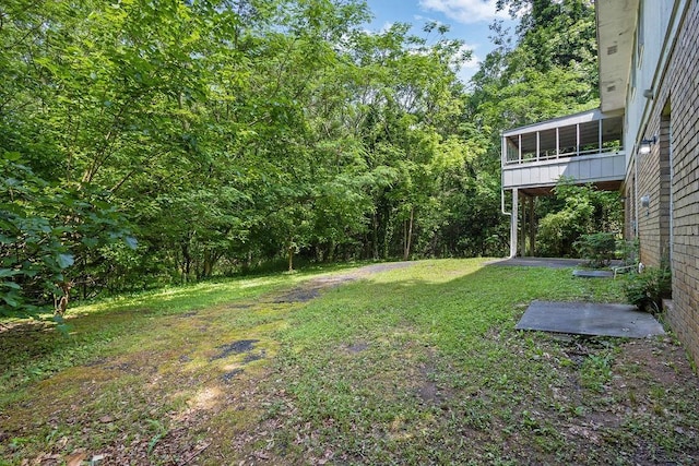 view of yard featuring a sunroom and a view of trees