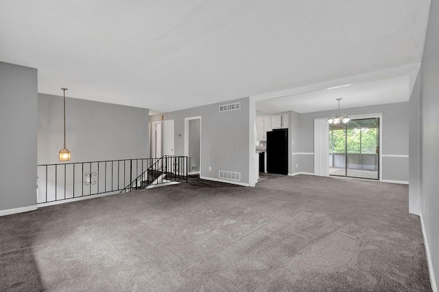 carpeted spare room featuring an inviting chandelier, baseboards, and visible vents