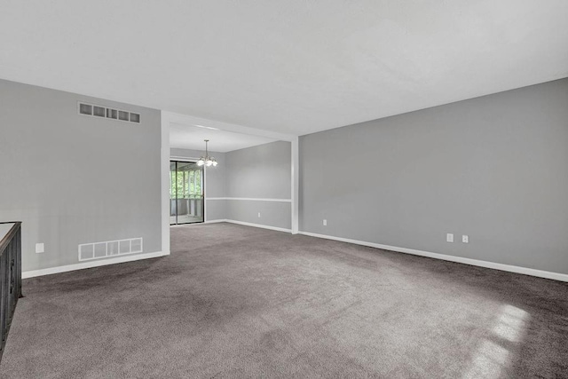 empty room featuring an inviting chandelier, dark carpet, and visible vents