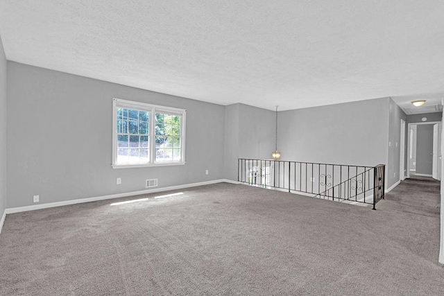unfurnished room featuring carpet floors, a textured ceiling, and baseboards