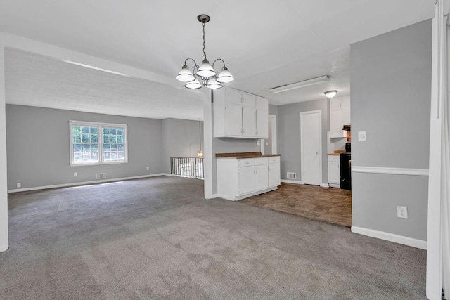 unfurnished living room featuring visible vents, baseboards, an inviting chandelier, and carpet